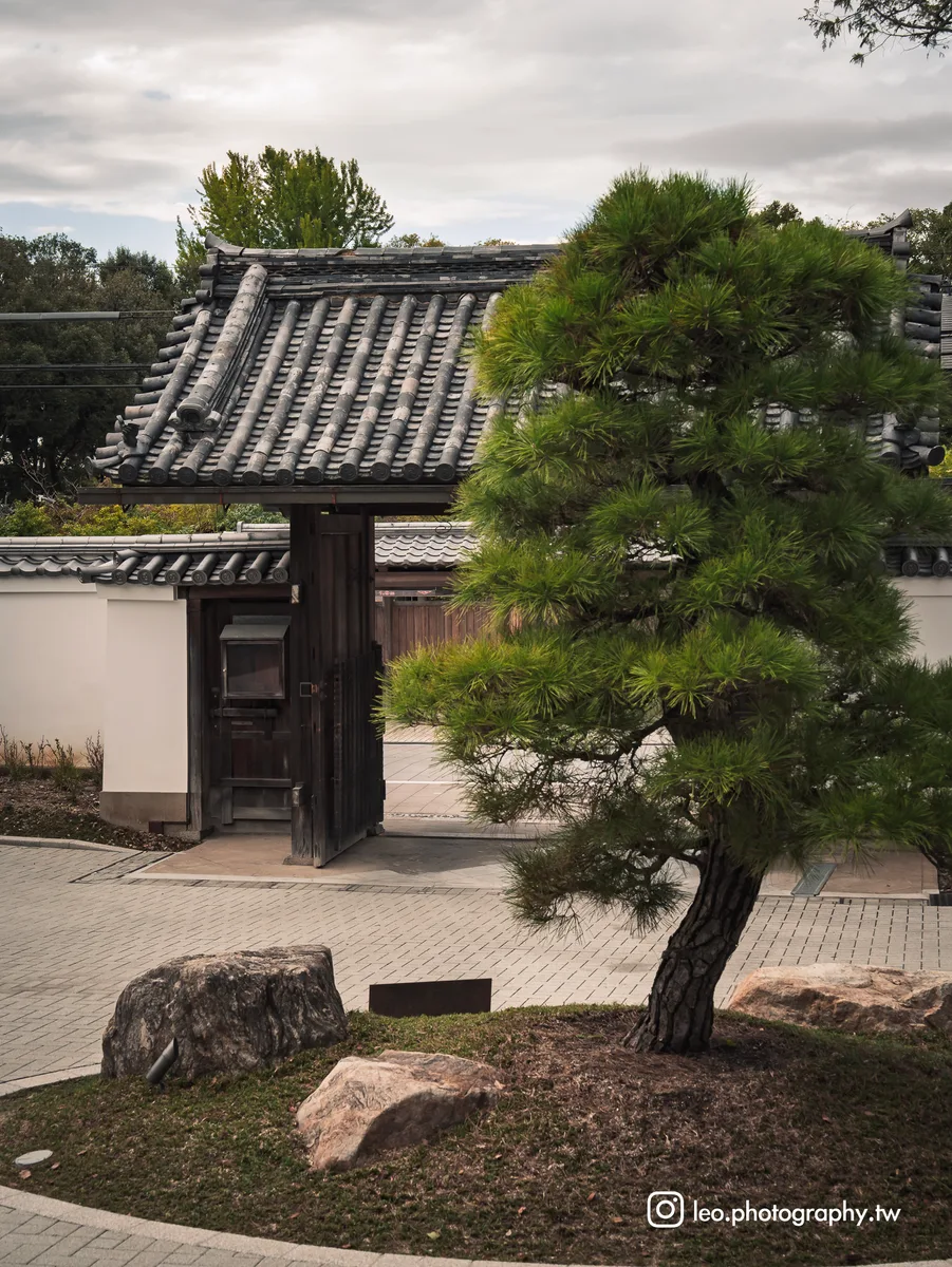 木門、松樹與石組錯落有致，形成入口的庭院景致。